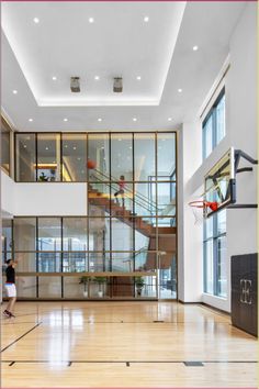 an indoor basketball court with glass walls and stairs