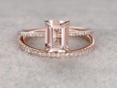 an emerald cut diamond ring set on top of a white surface with diamonds around it