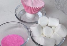 marshmallows and pink powder in bowls on a white counter top, next to a cupcake liner