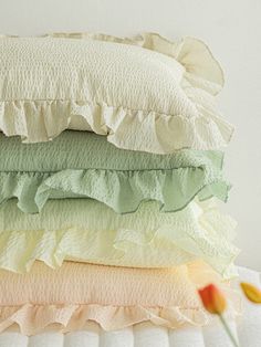 four pillows stacked on top of each other with ruffles and one flower in the foreground