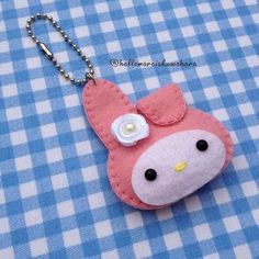 a pink hello kitty keychain on a blue and white checkered table cloth