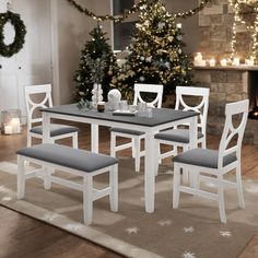 a dining room table and chairs in front of a fireplace with christmas decorations on the mantle