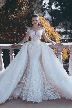 a woman in a white wedding dress standing on a balcony with her hands on the railing