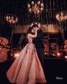 a man and woman standing next to each other in front of a chandelier