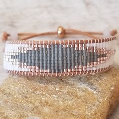 a white and grey beaded bracelet sitting on top of a rock