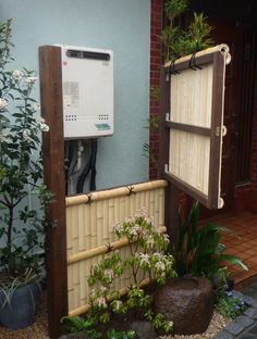 an outdoor water heater in the middle of a garden with rocks and plants around it