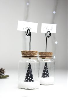 two glass jars with small black and white christmas trees in them, one has a name tag on the top