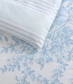 two blue and white pillows sitting next to each other on top of a bed cover