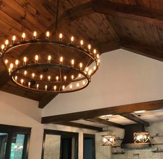 a chandelier hanging from the ceiling in a room with wooden beams and windows