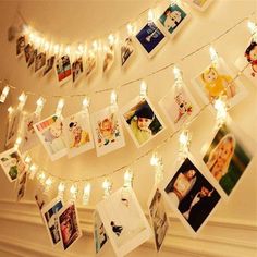 a string of pictures hanging from the ceiling with fairy lights strung over it and photos on them