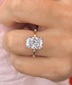 a close up of a person wearing a ring with a cushion cut diamond on it