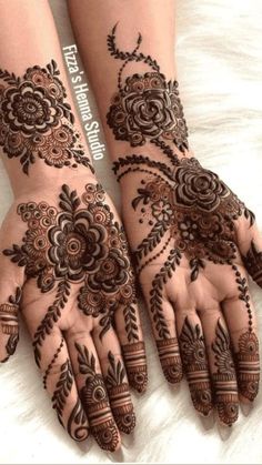 two hands with henna tattoos on them, one has flowers and the other has leaves