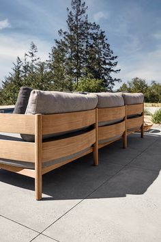 two wooden benches sitting next to each other on a cement ground with trees in the background