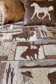 a bed covered in brown and white quilts with horse designs on the coverlet