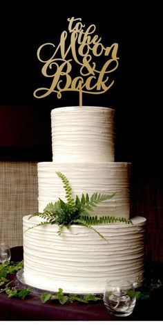 a wedding cake with the words just married written on top and fern leaves around it