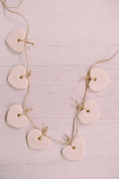 white ceramic hearts hanging from string on wooden background