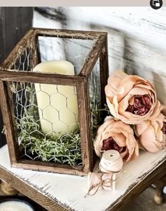 a candle and some flowers are sitting on a small table in front of a chicken wire cage