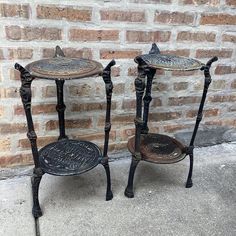 two black metal side tables sitting next to a brick wall