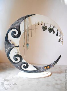 a crescent shaped mirror with jewelry hanging from it's sides and a cross on the other side