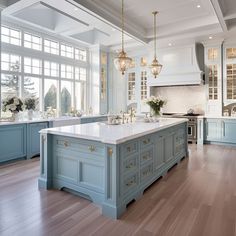 a large kitchen with blue cabinets and white counter tops, along with hardwood flooring