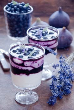 two desserts with blueberries and yogurt are on the table