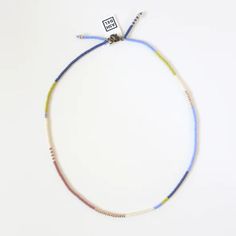 a multicolored beaded necklace on a white background with a tag attached to it