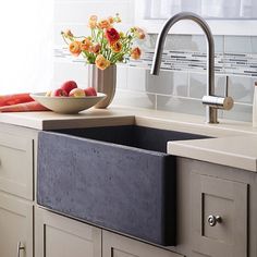 a kitchen sink with a bowl of fruit and flowers on the counter next to it