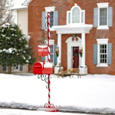 a red and white mailbox in front of a brick house with snow on the ground