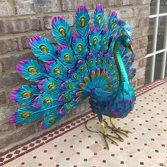 a peacock with its feathers spread out standing on a tile floor in front of a brick wall