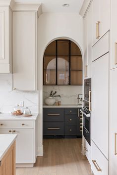 a kitchen with black and white cabinets, marble counter tops and wood flooring is seen in this image