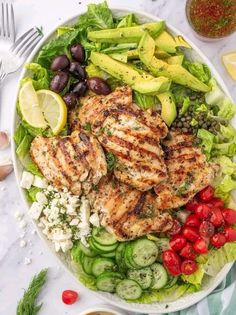 a salad with chicken, cucumbers, tomatoes and olives