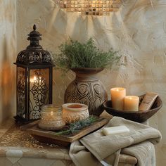 a candle and some candles are on a table next to two vases with plants in them