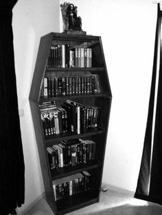 a black and white photo of a bookshelf in the corner of a room