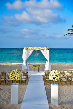 an outdoor wedding setup with white and yellow flowers on the aisle, overlooking the ocean