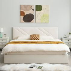 a white bed sitting in a bedroom next to two paintings on the wall above it