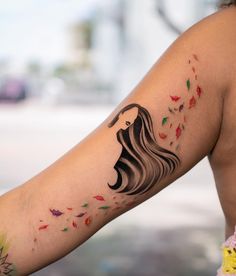 a woman's arm with a tattoo on it that has leaves falling from her hair