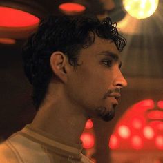 a close up of a person in a room with lights on the ceiling and one man looking off to the side