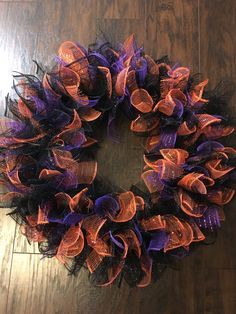 a purple and orange mesh wreath sitting on top of a wooden floor