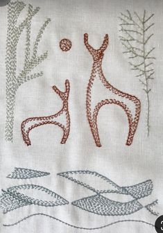 an embroidered piece of cloth with two people in the water and one person jumping up to catch a frisbee