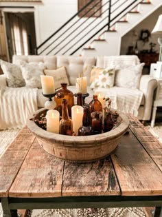 a wooden table topped with lots of bottles filled with candles next to a stair case