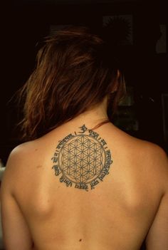 a woman's back with a flower of life tattoo on it