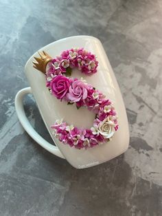 a white coffee cup with pink and white flowers in the shape of the letter s