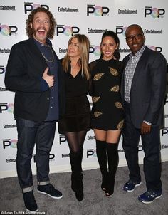 three people standing next to each other in front of a wall with the word entertainment on it