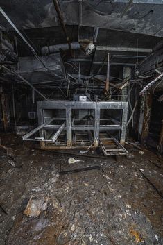 the interior of an abandoned building with debris on the floor and metal bars attached to the ceiling