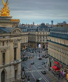 an aerial view of a city street with tall buildings and gold statues on the top