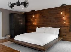 a large bed sitting in the middle of a bedroom next to a wooden headboard