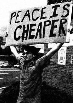 a man holding up a sign that says peace is cheaper