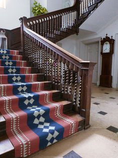 a stair case with blue, red and white rugs on the bottom handrail