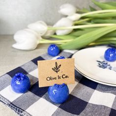 some blue candies are sitting on a checkered table cloth with flowers in the background