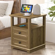 a small wooden table with drawers and a laptop on it's stand next to a bed